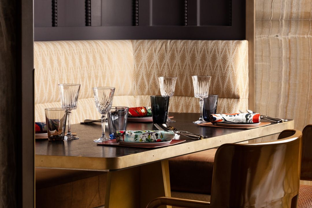 A dining booth with a table elegantly set with fine glassware and plates.